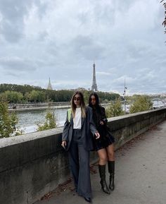 two women standing next to each other in front of the eiffel tower