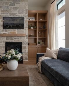 a living room filled with furniture and a fire place in front of a stone fireplace