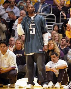 a man standing on top of a basketball court next to other men and people watching