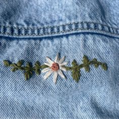 a close up of a denim jacket with embroidered flowers on it