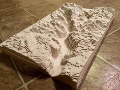 a book that is sitting on the floor with some paper cut out to look like mountains