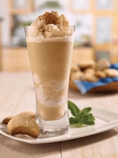 a glass filled with ice cream sitting on top of a white plate next to cookies