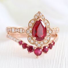 a close up of a red ring on a white surface with other jewelry items in the background