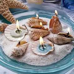 seashells and candles on a plate with sand