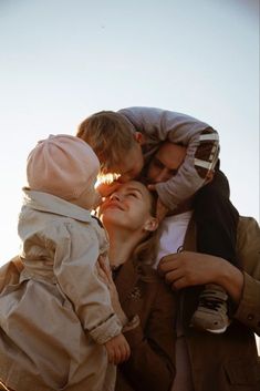 a woman and two children are kissing each other