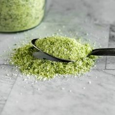 a spoon filled with green powder next to a jar