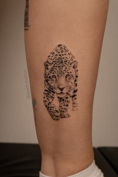 a black and white photo of a leopard tattoo on the right thigh, showing it's lower leg