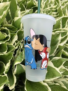 a plastic cup with an image of stitch and stitch on it next to some plants