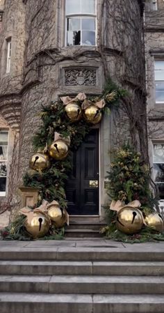 christmas decorations on the front steps of an old building with gold bells hanging from it's side