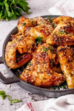 chicken wings in a skillet with herbs and seasoning sprinkled on top