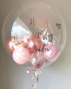 a clear balloon filled with pink and white balloons that say happy birthday to the widow