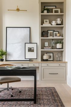 a desk with a chair and some pictures on the wall behind it in a home office