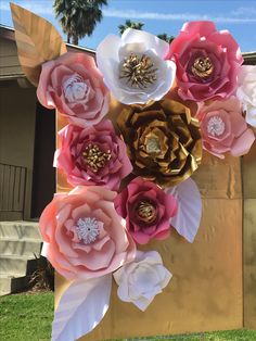 an arrangement of paper flowers is displayed in front of a wooden box on the grass