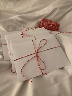 three wrapped gift bags with twine on them sitting on a white cloth covered bed