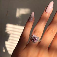 a woman's hand with a pink manicured nail polish and ring on it