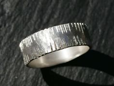 a silver ring sitting on top of a wooden table next to a black surface with light coming through it