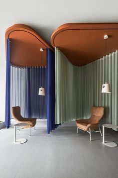 two chairs are sitting in the middle of a room with drapes hanging from the ceiling