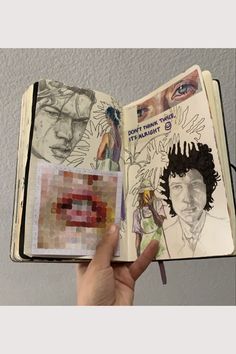 a hand holding an open book with drawings on it