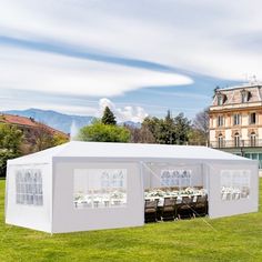 a large white tent set up in the middle of a field with tables and chairs