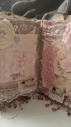 two decorative pillows with pink flowers and laces on them are sitting next to each other