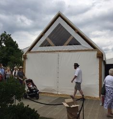 people are walking around in front of a building with a white sheet on the roof