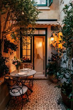 an outdoor patio with potted plants on the side and a table set for two