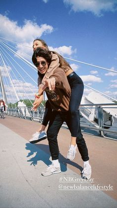 two people on skateboards in front of a bridge and blue sky with wispy clouds