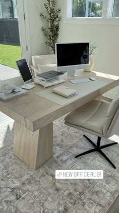 an office desk with a computer on top of it in front of a large window