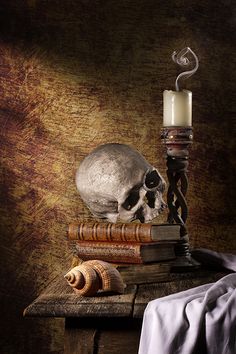 a skull sitting on top of books next to a candle