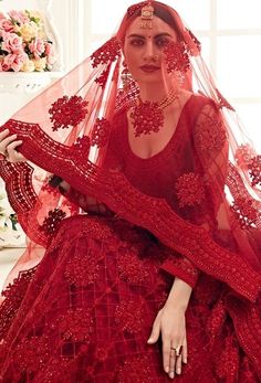 a woman wearing a red wedding gown and veil