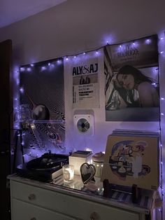 a room with purple lights and various items on the wall, along with posters and cds