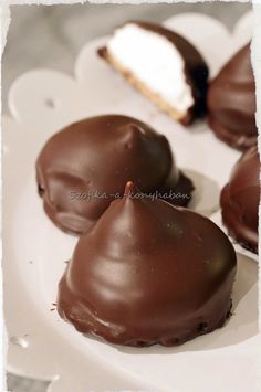 three chocolate covered desserts on a white plate