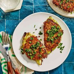 two pieces of food on a white plate with silverware next to it and a blue tiled table