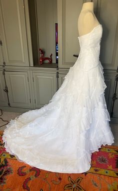 a white wedding dress on display in front of a wall with many closets behind it