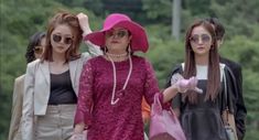 three women in pink hats and sunglasses walking down the street with their hands on their head