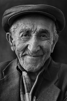 an old man wearing a hat and looking at the camera with a smile on his face