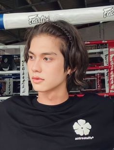 a young man standing in front of a boxing ring wearing a black t - shirt