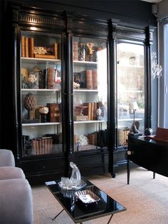 a living room filled with furniture and bookshelves next to a glass doored window