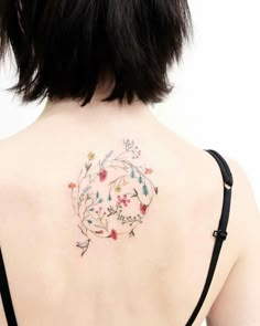 the back of a woman's shoulder with flowers and leaves tattooed on her chest