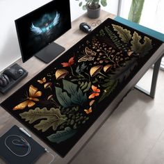 a computer desk with two monitors on it and an art work area in the background