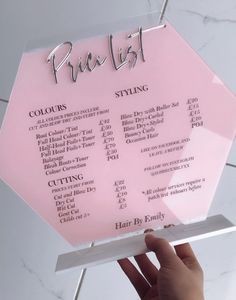 a person holding up a pink sign with the words pral list on it in front of a marble wall