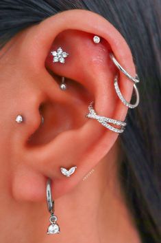 an ear with three different types of piercings on it's sides and two smaller ones