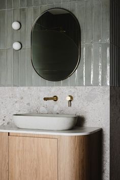 a white sink sitting under a mirror next to a wall mounted faucet in a bathroom