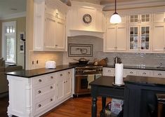 a large kitchen with white cabinets and black counter tops, along with an island in the middle