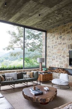 a living room filled with furniture next to a stone wall covered in windows and a flat screen tv on top of a wooden table