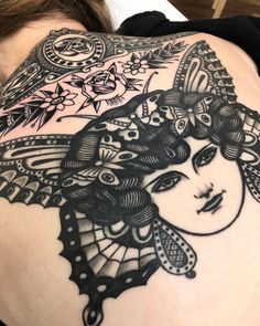 a woman's back with an intricate tattoo design on her upper arm and shoulder