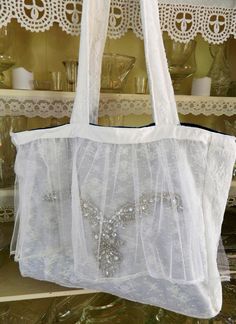 Very Large Bride's  Fabric Tote Bag This bag is one of a new line of very large and roomy totes that feature a 5 inch removable flat bottom.  We took some pieces of a vintage wedding dress and created a very chic and romantic bag. What a story the dress could tell!  This bag would be perfect for the bride to carry all the needful things required for the dressing room.... such as shoes, makeup, robes, etc. It is completely lined.  The lining is a soft blue velvet fabric.  This could be your something blue!  The back of the bag features a white lace overlay. 2 27 inch straps sewn from a sturdy white fabric overlayed with white lace fabric 15 inches deep 18 inches across 5 inch flat bottom inside to which we added a removable insert for added stability.  You can take the insert out when you c Elegant Large White Bag, White Tote Shoulder Bag For Wedding, Wedding Gift Bag Tote, Wedding Gift Tote Bag, Bride Tote Bag, Bride Tote, Blue Velvet Fabric, Lace Bag, White Lace Fabric