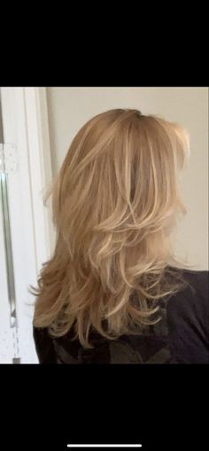 the back of a woman's head with long, blonde hair in front of a door