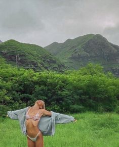 a woman standing in the grass with her arms stretched out and head tilted to the side