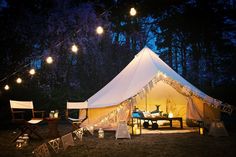 a white tent with lights hanging from it's sides and some chairs around it